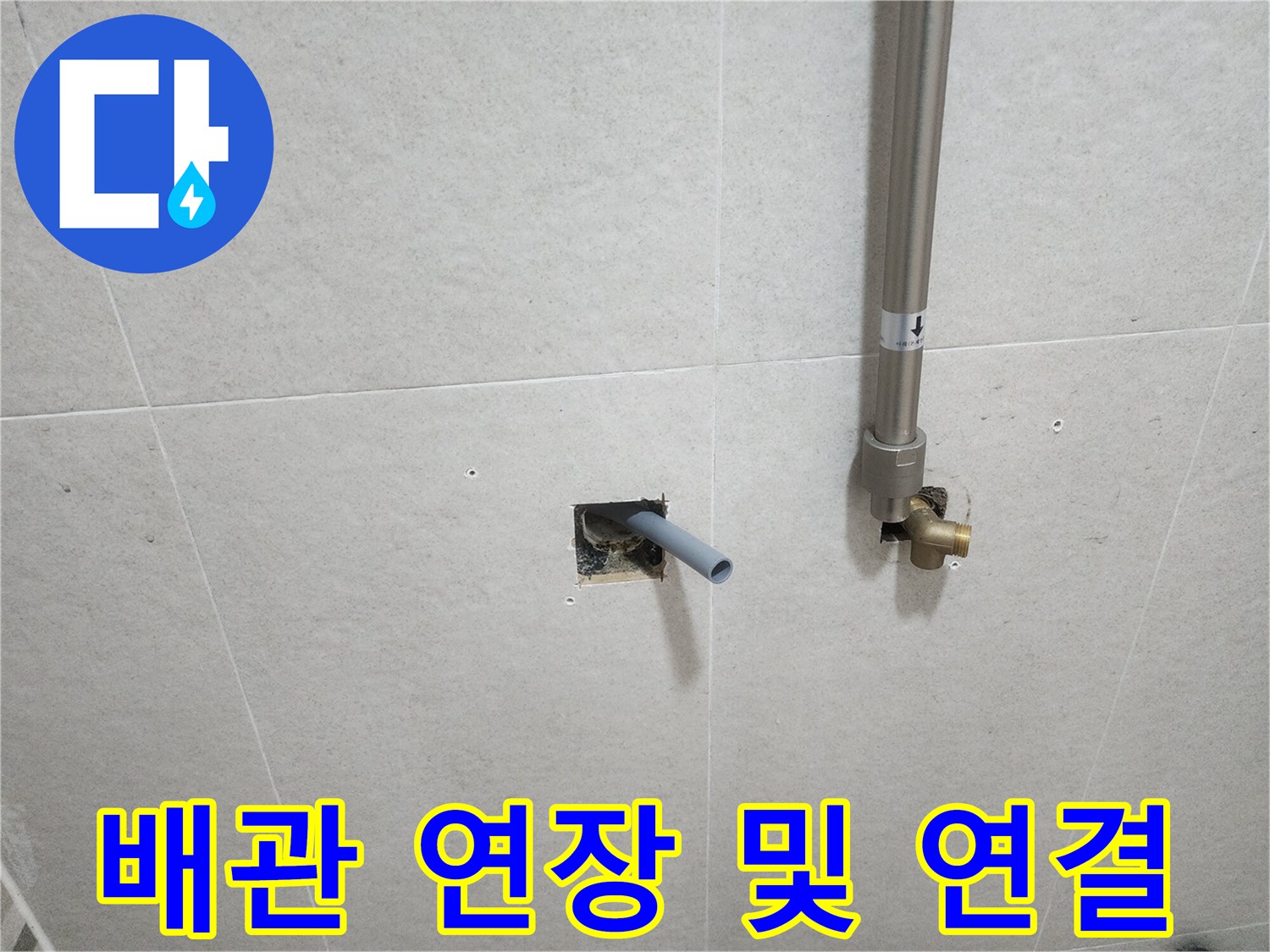 타일 벽면 밖으로 돌출되어 나온 은색 배관과 황동 부속