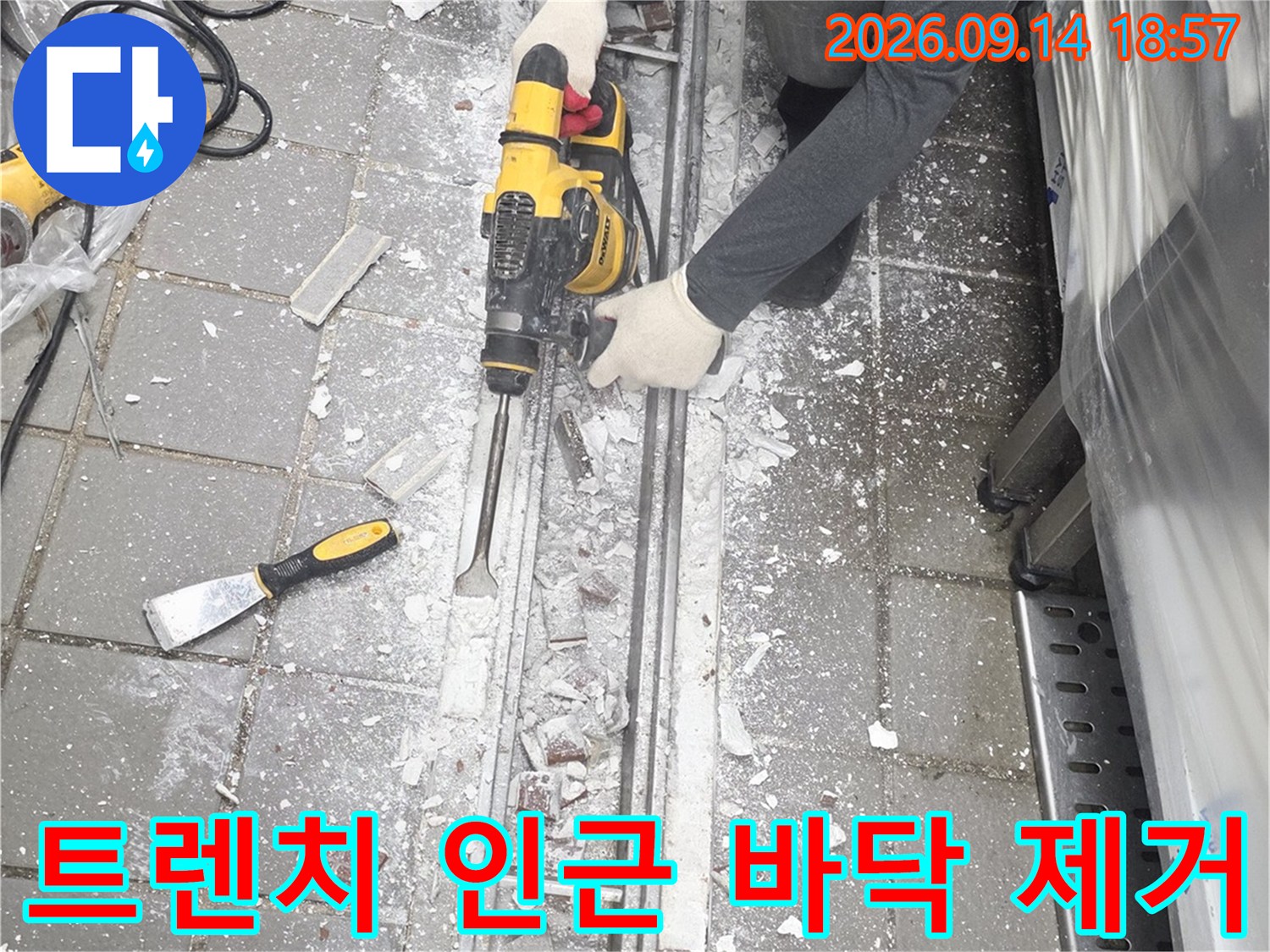 드릴 장비를 사용하여 트렌치 옆 타일 층을 파헤치는 작업 현장