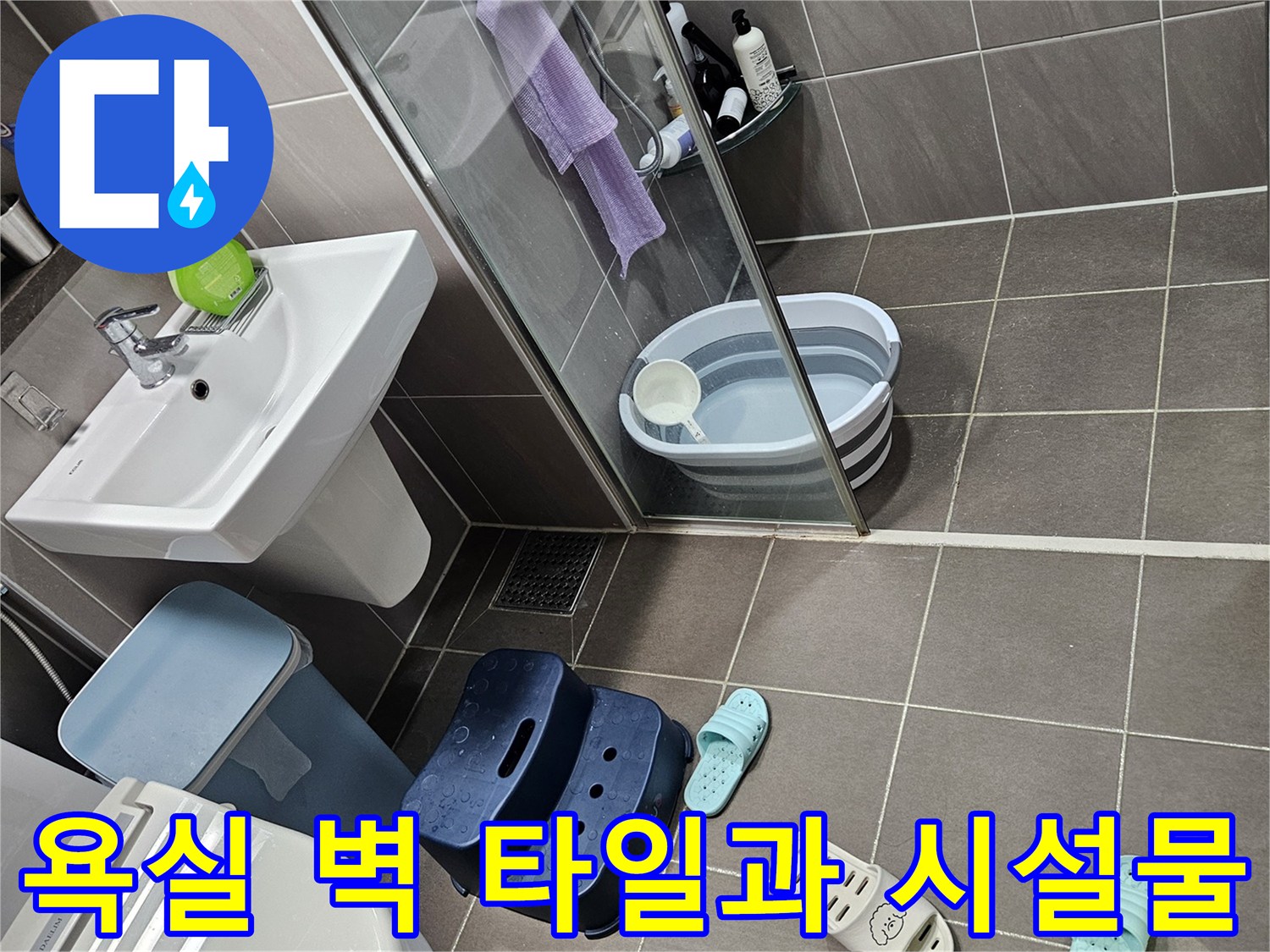 회색 타일 벽면과 세면대 하단 배관 부근 사진