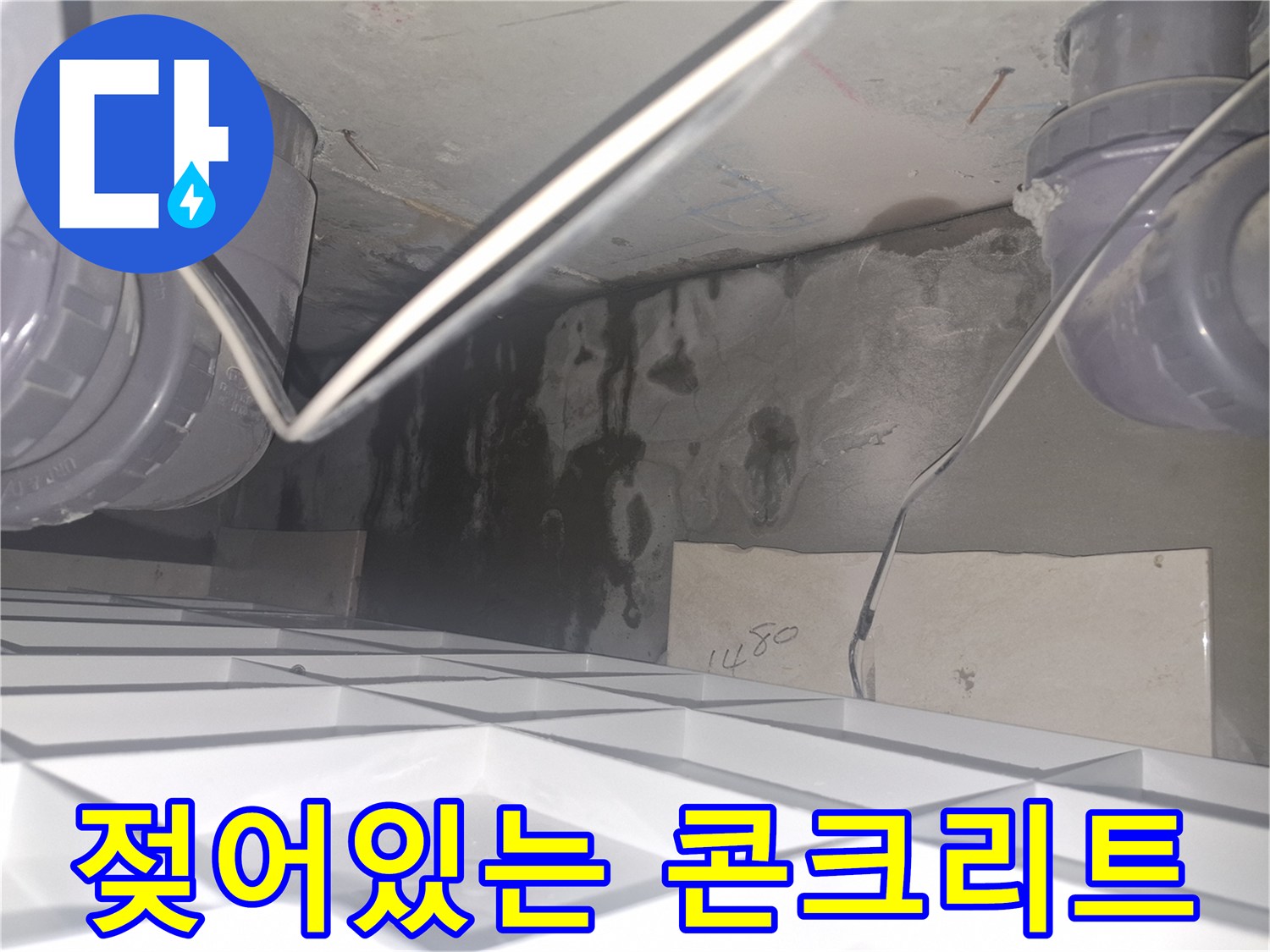 배관 하부층 - 습기로 인해 짙게 변한 콘크리트 벽면과 배관 연결 부위