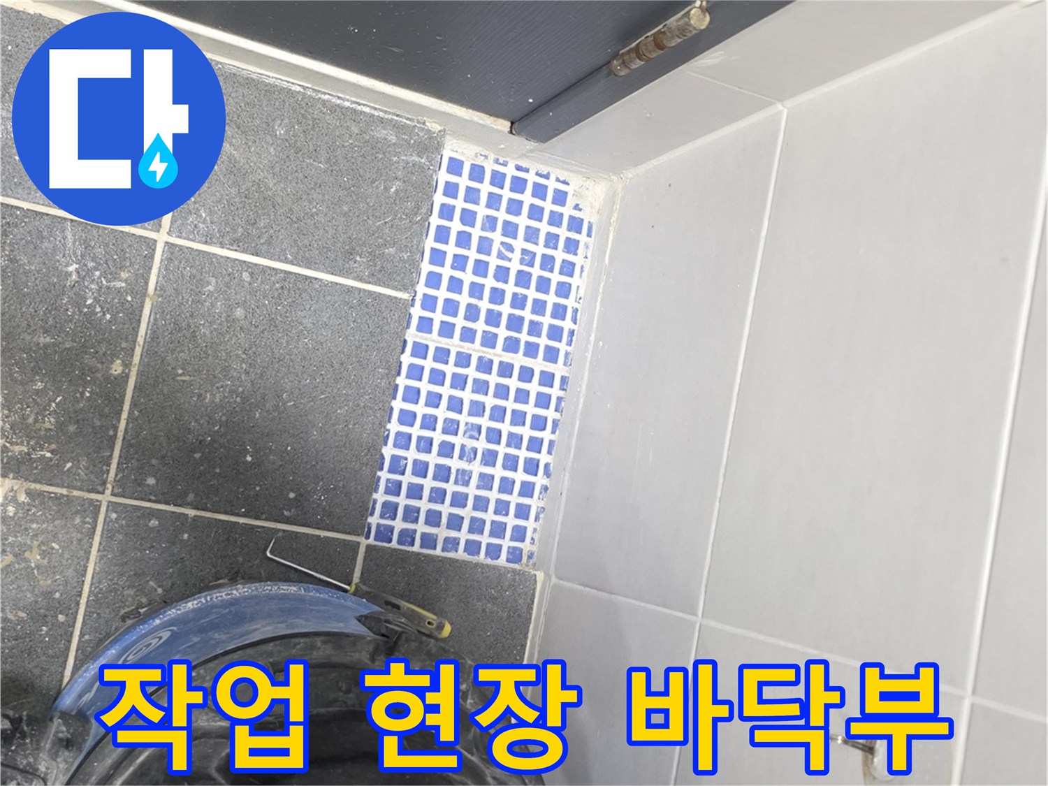 화장실 문 옆 타일과 작업용 진공 청소기 모습입니다.