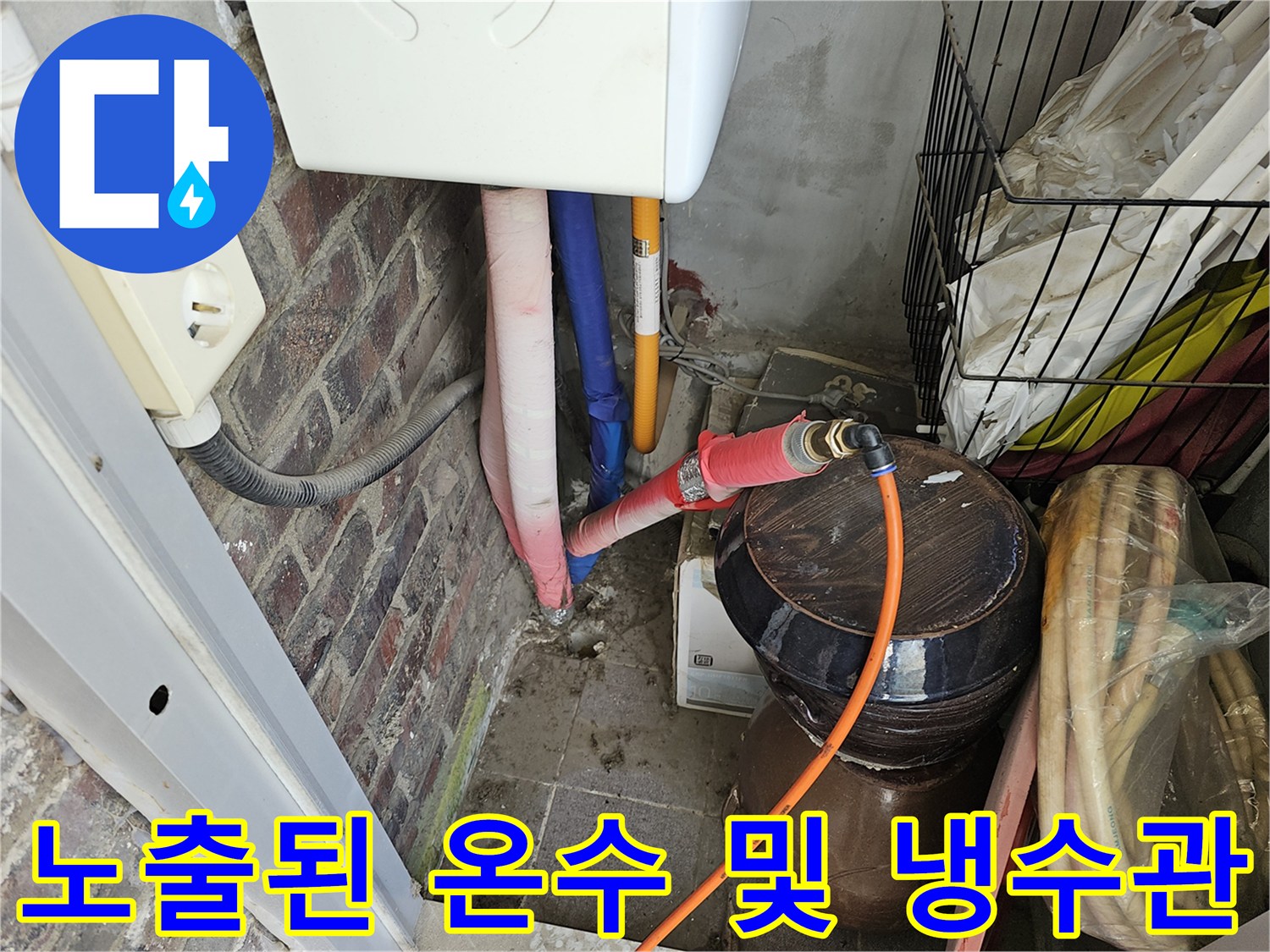 세면대 하부 벽면에 연결된 분홍색과 파란색 배관의 근접 촬영