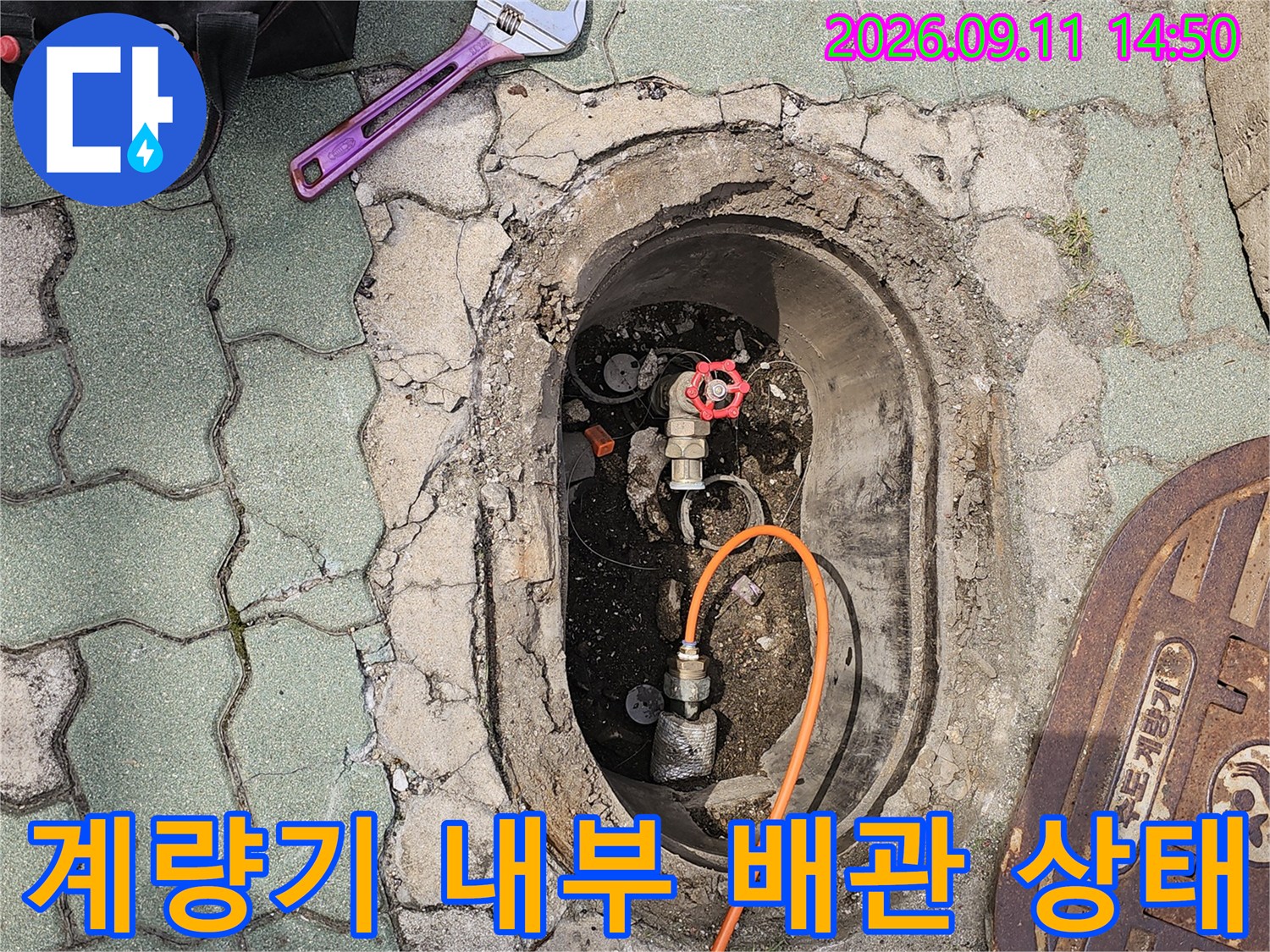 수도 계량기함 안쪽의 붉은색 밸브와 주황색 호스 연결 부위 상세 사진