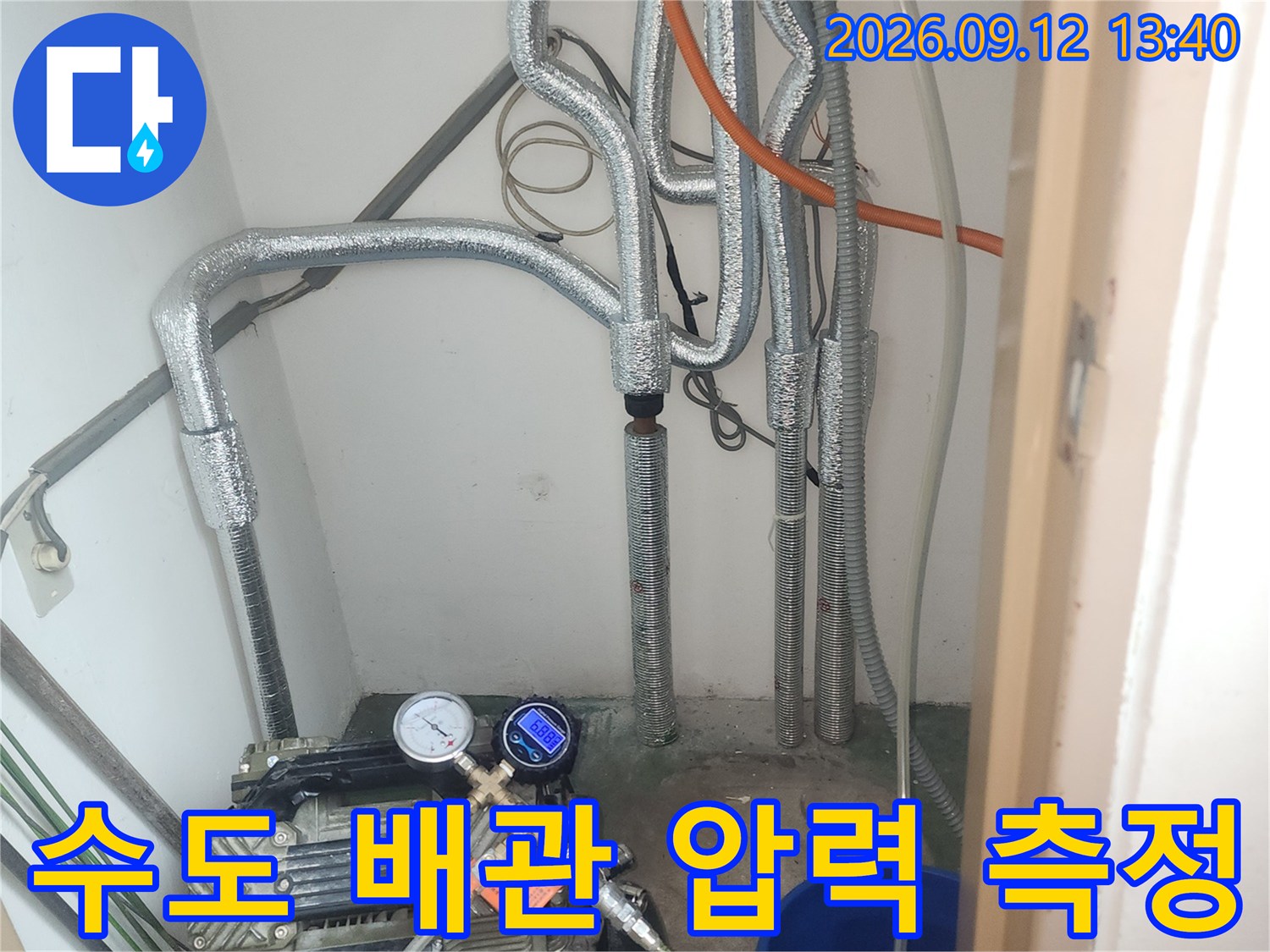 은색 보온재로 감싸진 배관에 연결된 공압 검사 장치와 게이지입니다.
