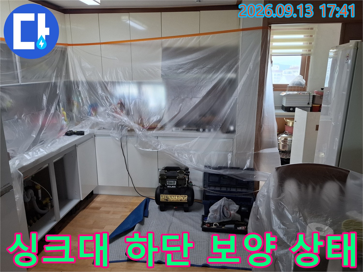 누수 점검을 위해 싱크대 주변을 비닐로 덮어 보호하고 있는 모습입니다.