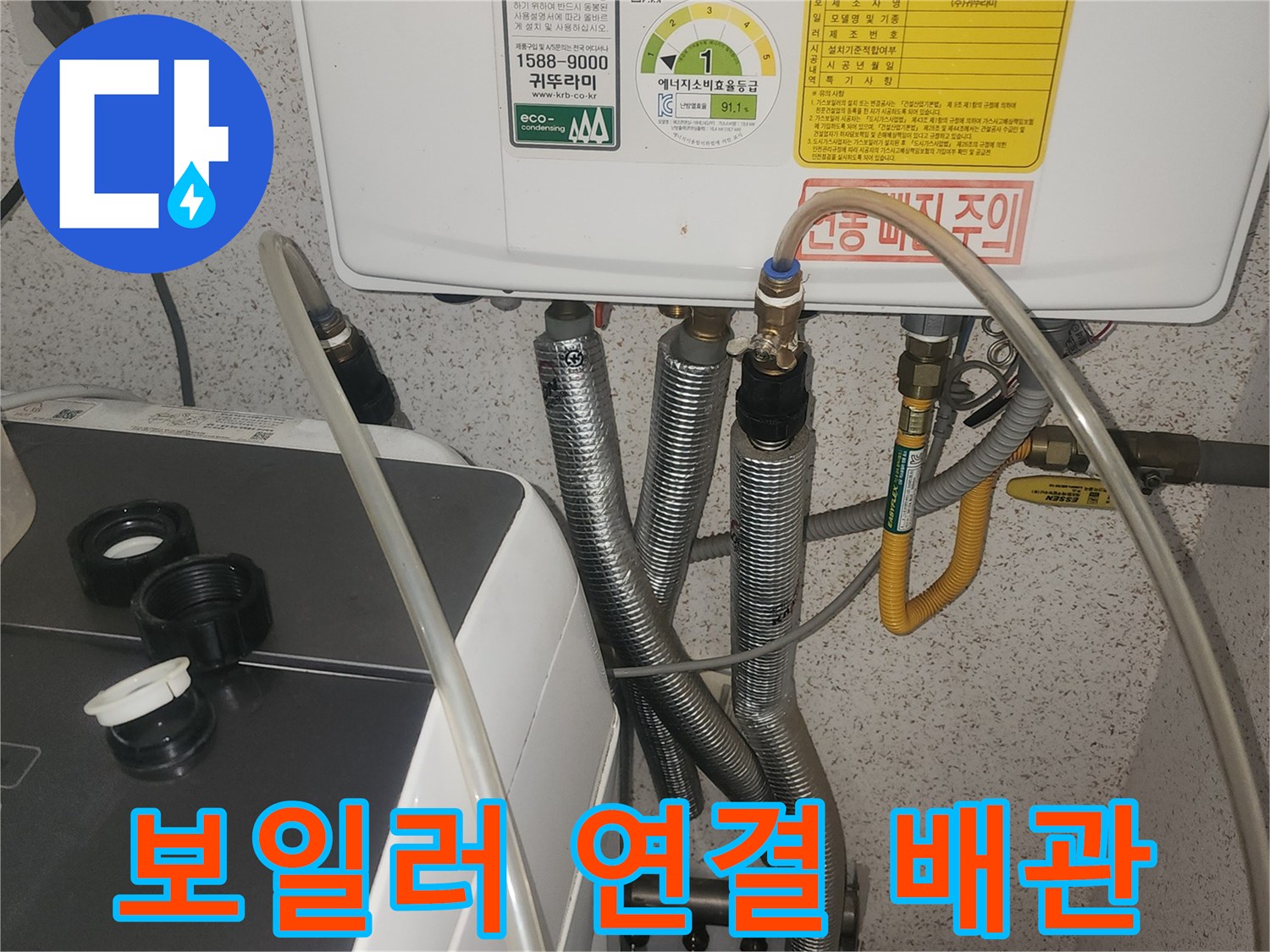 보일러 아래쪽의 금속 배관과 노란색 유연한 관 연결부