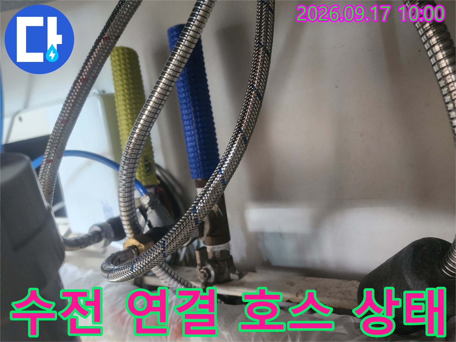 금속 재질의 꼬임형 배관과 파란색 보온재가 설치된 싱크대 하부 배관 상세 사진입니다.