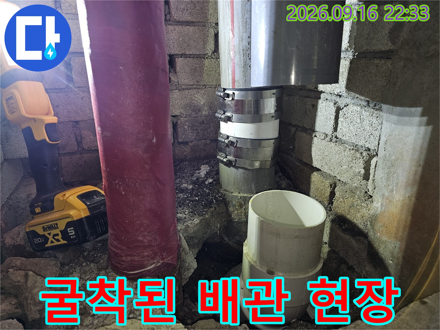 벽면을 굴착하여 노출시킨 배관 연결 부위와 작업용 랜턴 모습