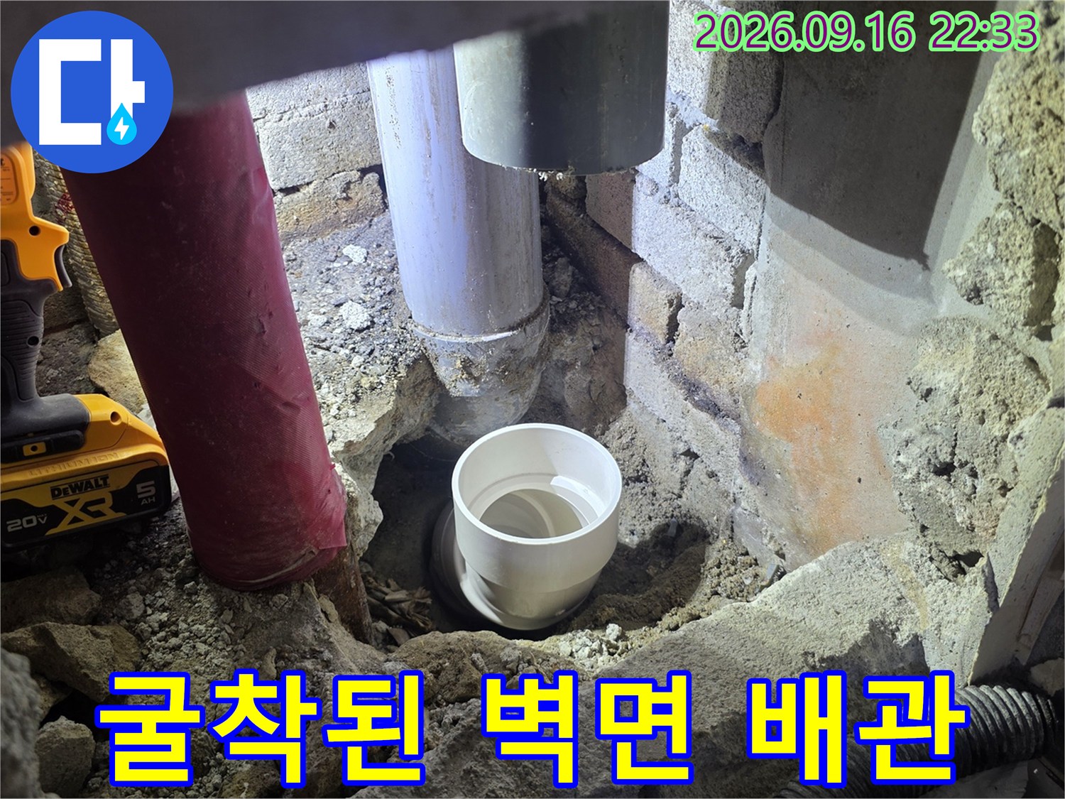 벽체 내부의 흰색 배관과 주변 흙이 드러난 누수 보수 현장입니다.